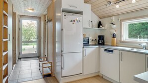 Een moderne keuken met een inbouwkoelkast, een koffiezetapparaat en een raam met uitzicht op groen.