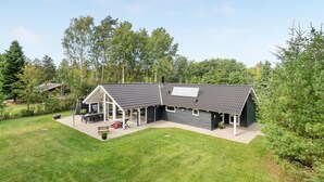 Een modern huis met een ruime achtertuin, een overdekt terras en een aparte garage.