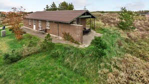 Een bakstenen gebouw met een overdekte patio, omringd door grasvelden en enkele bomen.