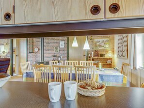 Un coin repas chaleureux avec des chaises et une table en bois, un mur de briques orné d’œuvres d’art et un buffet en bois placé au-dessus de la table.