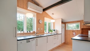 A modern kitchen with wooden paneling, a dishwasher, a sink, and a window overlooking greenery. - "Alisia" - 400m from the sea by Interhome (Hals)