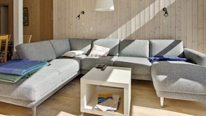 A modern living room with a grey sectional sofa, a white coffee table, and a wooden floor. - "Alisia" - 400m from the sea by Interhome (Hals)