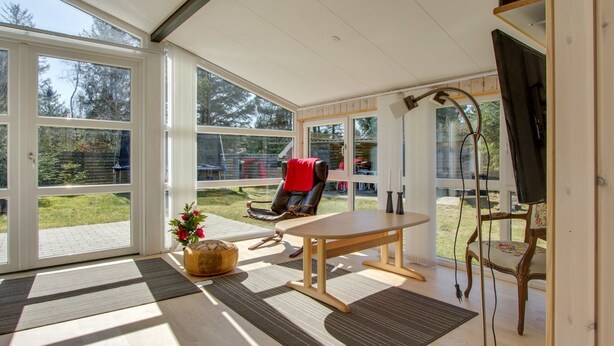 A spacious room with large windows, a wooden table, a comfortable chair, and a television. - "Alisia" - 400m from the sea by Interhome (Hals)