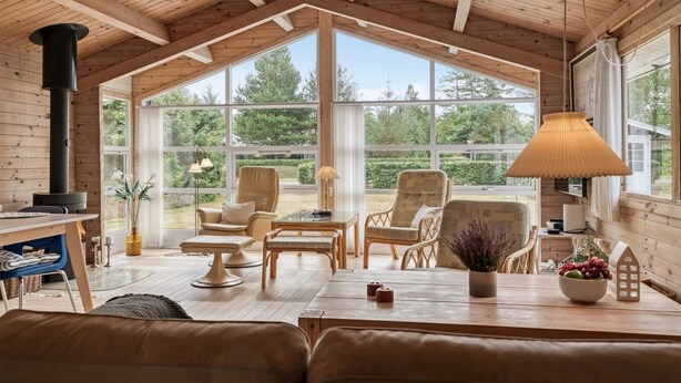 A cozy wooden cabin interior with a large open window, a fireplace, and comfortable seating. - "Jannus" - 550m from the sea by Interhome (Hals)