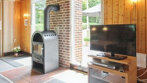 A room with a wood-burning stove, a television on a wooden stand, and a sliding glass door leading to an outdoor area. - "Friedeman" - 29km from the sea by Interhome (Toftlund)