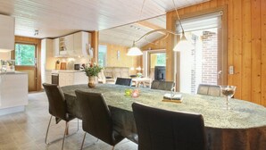 A modern kitchen with a central island, wooden walls, and a dining area with a round table and chairs. - "Friedeman" - 29km from the sea by Interhome (Toftlund)