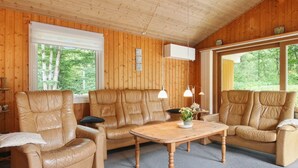 A cozy room with wooden walls, a leather sofa, a wooden coffee table, and large windows offering a view of greenery. - "Friedeman" - 29km from the sea by Interhome (Toftlund)