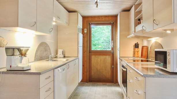 A modern kitchen with white cabinets, a wooden door, and a window. - "Friedeman" - 29km from the sea by Interhome (Toftlund)