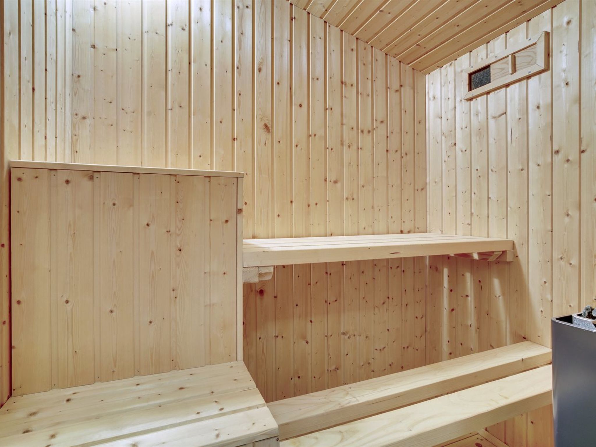 Una sauna de madera con bancos y un ventanal pequeño.