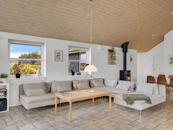 A modern living room with a wooden ceiling, a sofa set, a coffee table, and a fireplace.