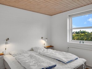 Une chambre à coucher avec un lit, des lampes de chevet, une fenêtre donnant sur un paysage agréable et un radiateur.