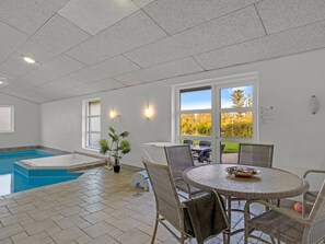 Un espace piscine doté d’un jacuzzi, de coins salon extérieurs et offrant une vue sur les arbres.