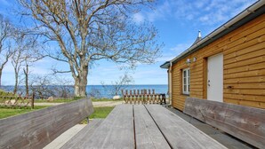 A wooden cabin with a picnic table and benches, overlooking a body of water. - "Alfred" - 25m from the sea by Interhome (Gudhjem)