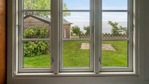 A window with a view of a grassy yard, a wooden structure, and a fence. - "Alfred" - 25m from the sea by Interhome (Gudhjem)