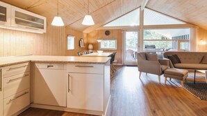 A modern kitchen with wooden cabinets, a central island, pendant lighting, and a dining area with a sofa and chairs. - "Elsemaria" - 1.3km from the sea by Interhome (Løkken)