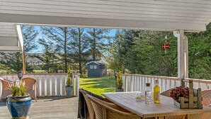 A covered patio with a wooden table, wicker chairs, and a small shed in the background. - "Elsemaria" - 1.3km from the sea by Interhome (Løkken)