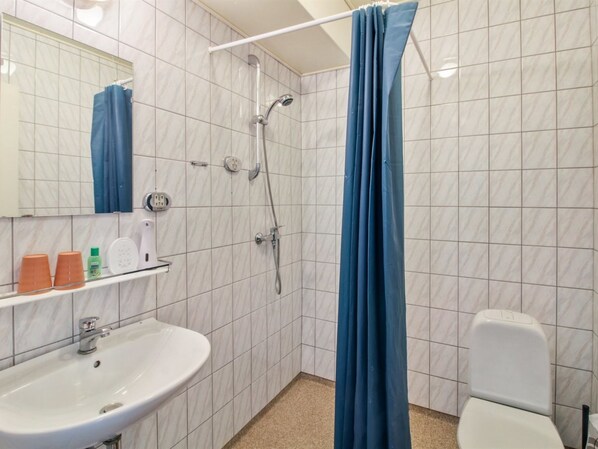 A bathroom with a white sink, a toilet, a shower with a blue curtain, and a mirror.