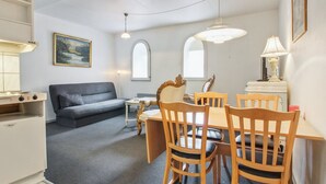 Un espace de vie compact comprenant un coin repas, un canapé et une kitchenette.