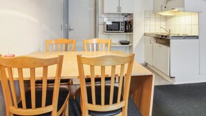 Une cuisine de taille réduite, avec des meubles blancs, un four à micro-ondes et une machine à café.