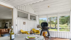 A covered outdoor dining area with a table set for two, a grill, and a view of the outdoors. - "Gloria" - 2.5km from the sea by Interhome (Blokhus)