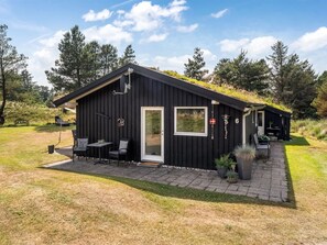 Une cabane noire dotée d’une terrasse, d’une porte et d’une fenêtre.