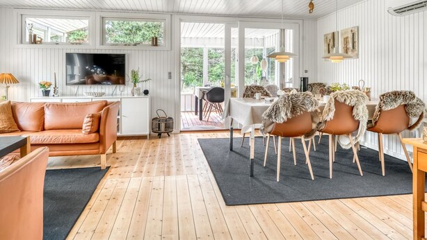 A spacious living area with a wooden floor, a sofa, a dining table with chairs, and a TV mounted on the wall. - "Gloria" - 2.5km from the sea by Interhome (Blokhus)