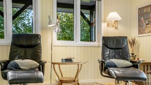 A room with two leather chairs, a small round table, and a floor lamp.
