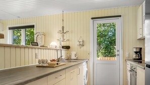 A compact kitchen with a sink, stove, and a window with a view of greenery.