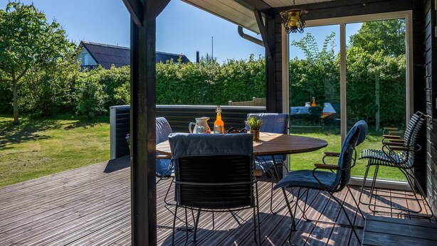 An outdoor patio with a wooden deck, a round table, and metal chairs.
