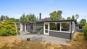 Une maison moderne de plain-pied, dotée d’une terrasse, d’une antenne parabolique et d’une grande fenêtre.