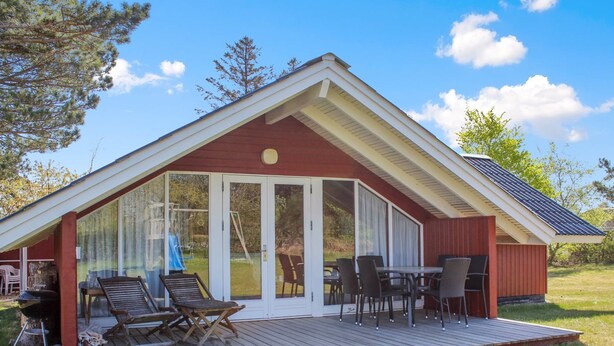Een gelijkvloers huis met een overdekte patio, een schuifpui en een klein terras met stoelen en een tafel.