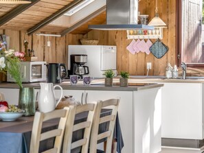 Una cocina con una isla central, armarios de madera, una campana extractora de acero inoxidable y una lámpara colgante.