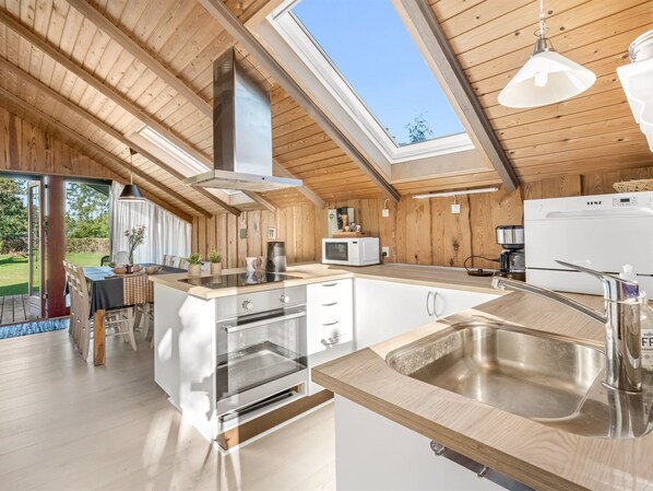 A modern kitchen with a large island, stainless steel appliances, and a skylight.