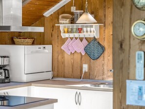 A kitchen with a white refrigerator, a coffee maker, and a wooden wall.