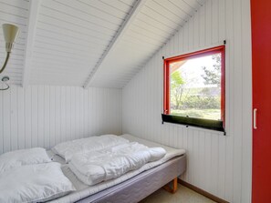 A single bed with white bedding in a room with white walls and a sloped ceiling.