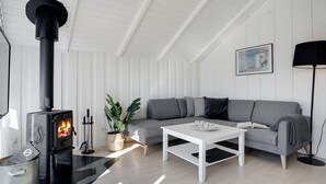 A modern living room with a black wood-burning stove, a grey sofa, a white coffee table, and a floor lamp.