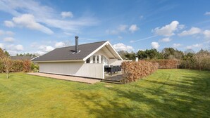 A single-story house with a sloped roof, a chimney, and a covered porch with outdoor seating.