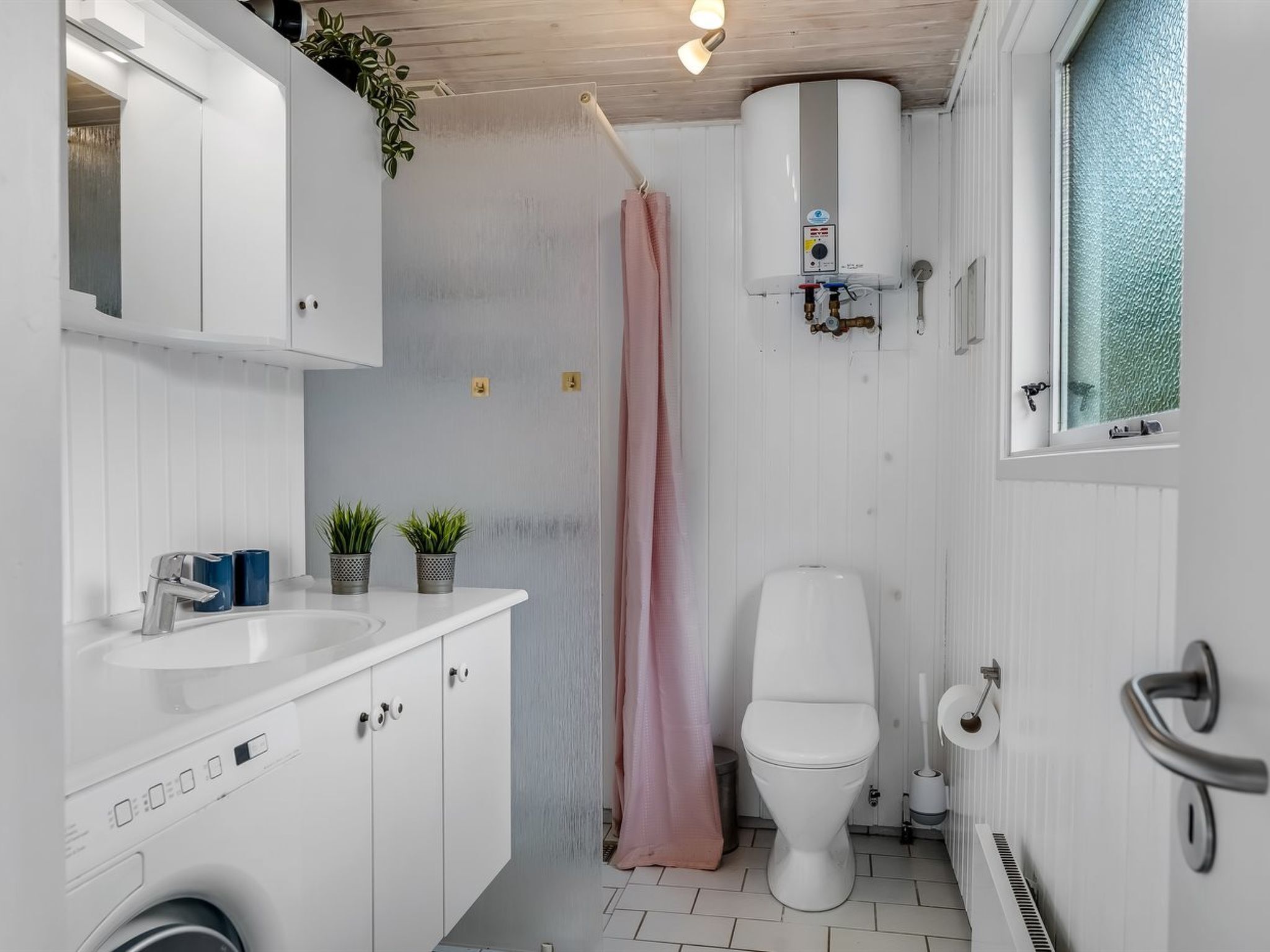 A compact bathroom with a white sink, a toilet, and a shower curtain.