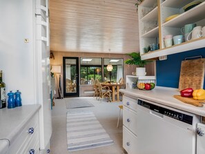 A modern kitchen with white cabinetry, a Siemens dishwasher, and a dining area with a table and chairs.