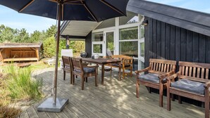 A wooden deck with outdoor furniture, including a table and chairs, and a large umbrella.