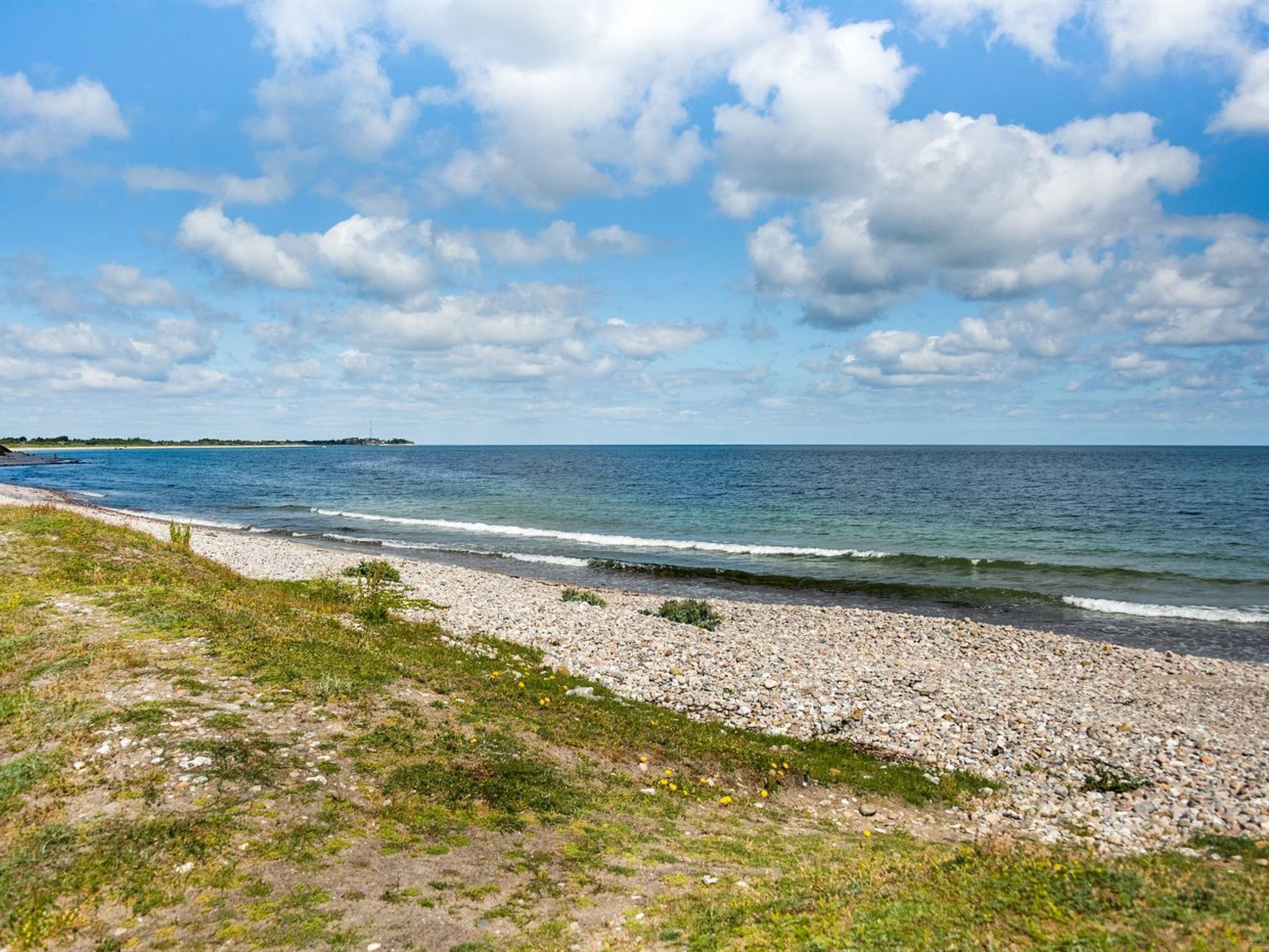 A beach with a pebbly shore and a clear view of the sea.