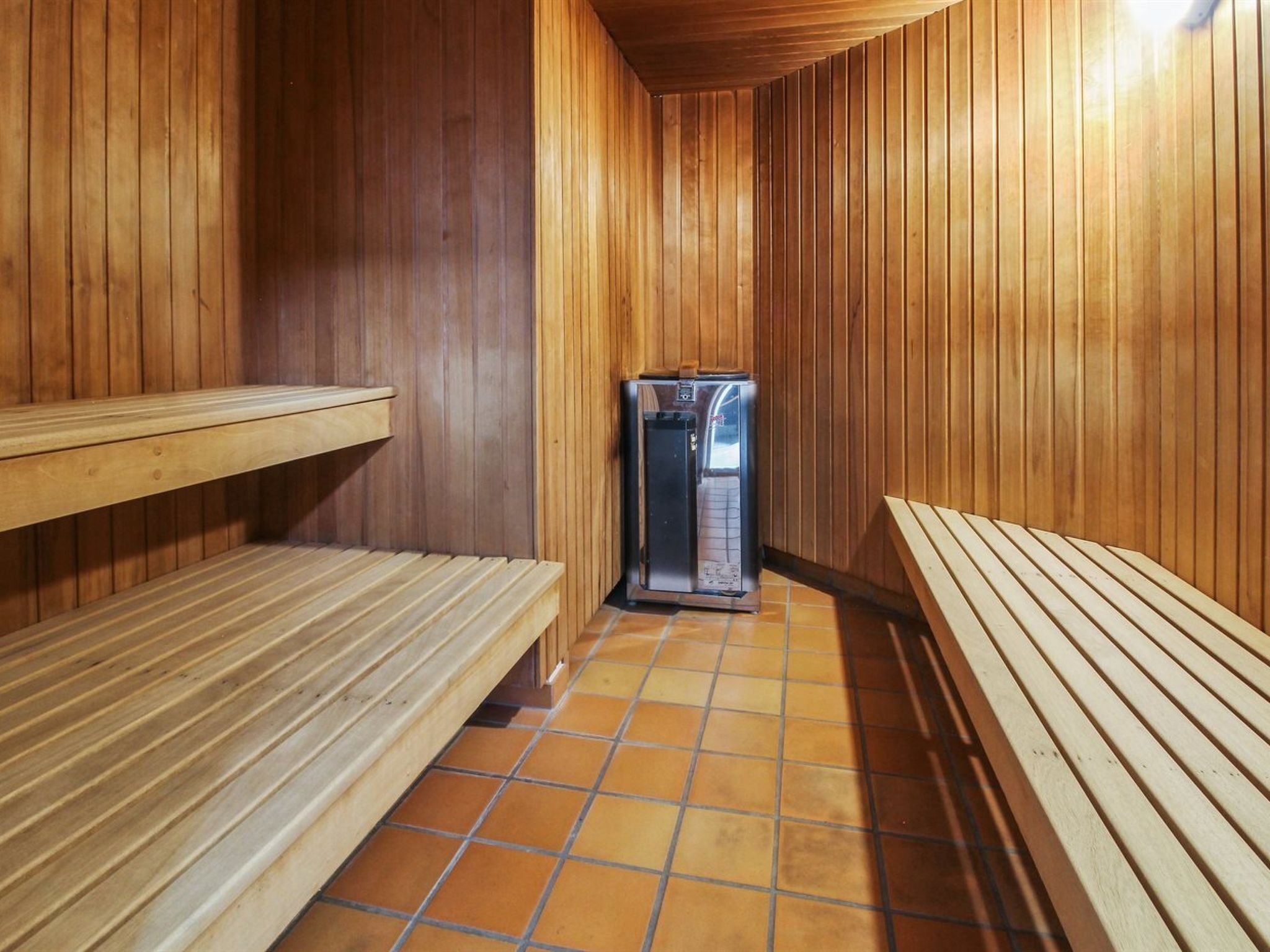 A sauna room with wooden benches and a sauna unit.