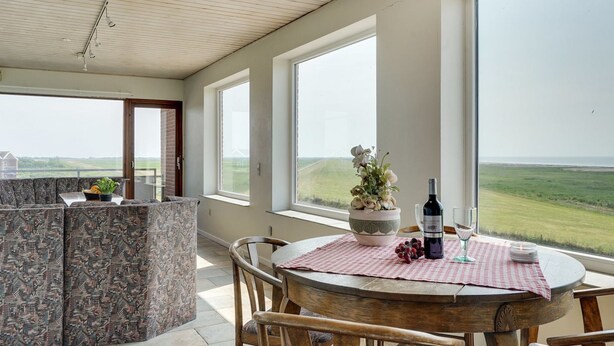 A dining area with a view of the countryside, a round wooden table, and a potted plant. - "Stilla" - 35km from the sea by Interhome (Højer)