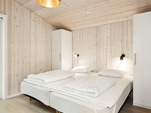 Ein modernes Schlafzimmer mit Holzboden, einem Bett mit weißer Bettwäsche und zwei Wandleuchten.
