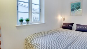 A bedroom with a bed, two potted plants on the windowsill, a wall-mounted light, and a framed picture. - "Sofine" - 250m from the sea by Interhome (Løkken)