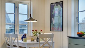 A dining area with a white table and chairs, a hanging pendant light, a poster on the wall, and a window with a view of the outside. - "Sofine" - 250m from the sea by Interhome (Løkken)