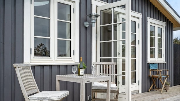 A wooden deck with a table and two chairs, a bottle of wine, and a glass on the table. - "Sofine" - 250m from the sea by Interhome (Løkken)