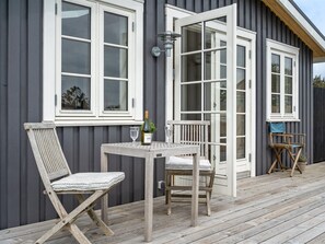 A wooden deck with a table and two chairs, a bottle of wine, and a glass on the table. - "Sofine" - 250m from the sea by Interhome (Løkken)