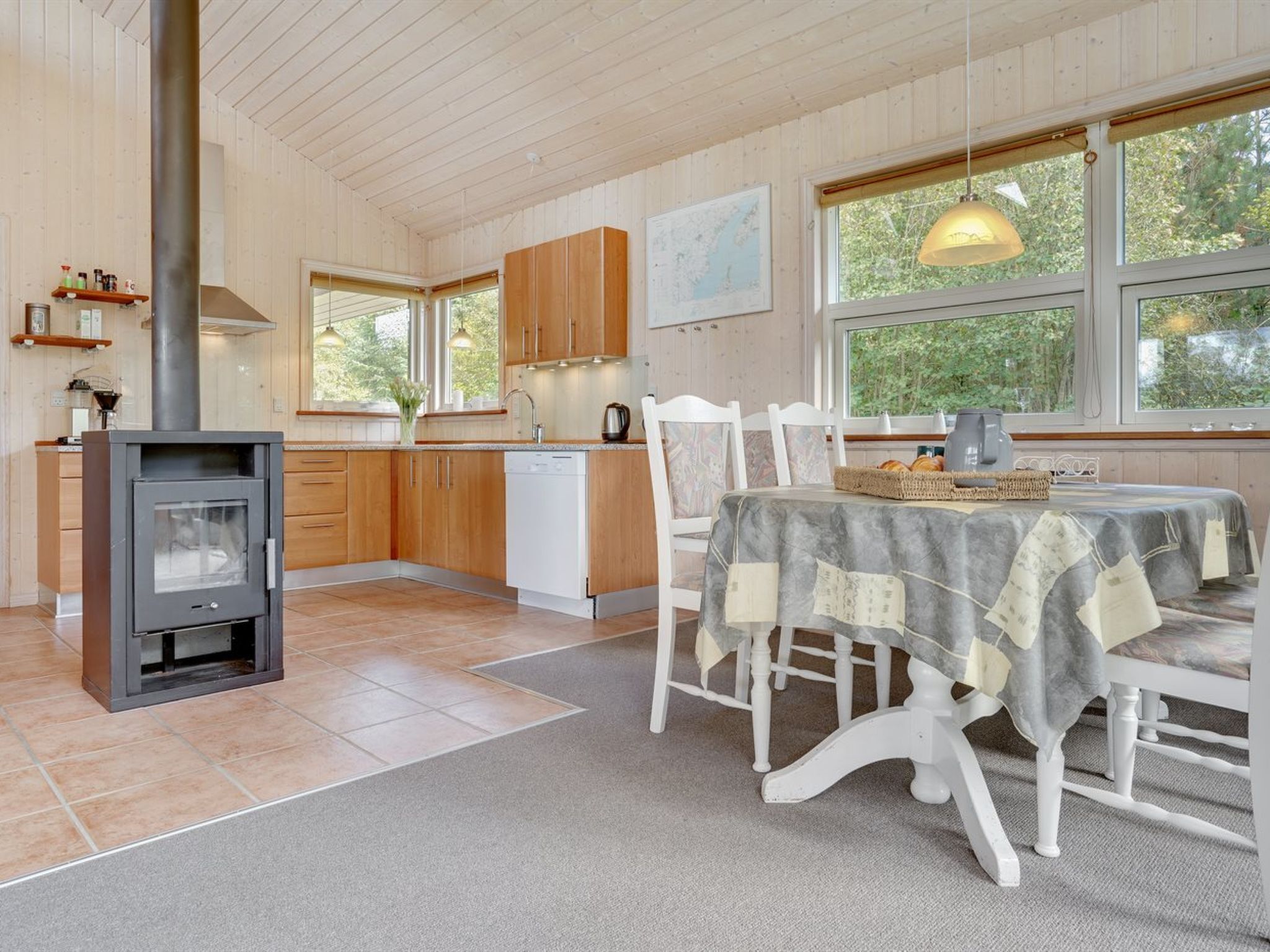 Une cuisine moderne avec des meubles en bois, une cuisinière encastrée et un coin repas comprenant une table et des chaises.