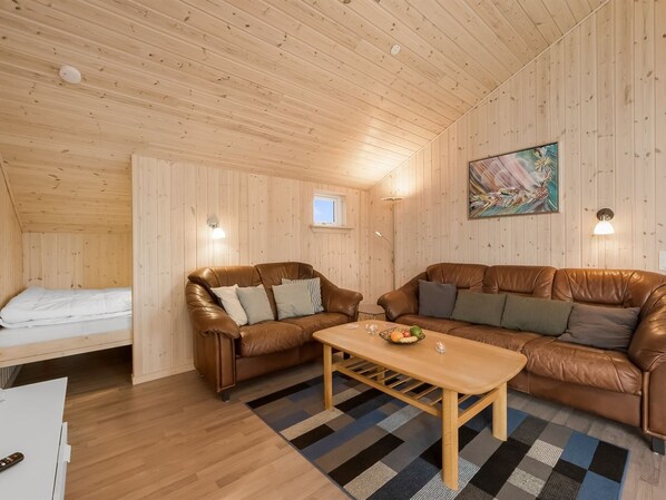 A cozy room with a brown leather sofa, a wooden coffee table, and a bed with white bedding.